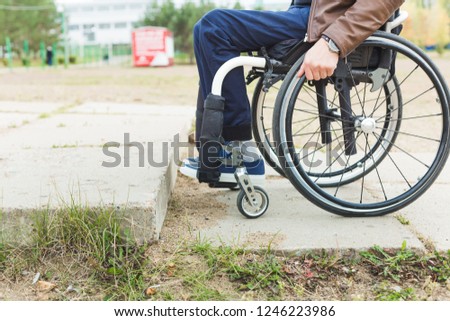 Young man in wheelchair with his assistant on a stroll through the park.