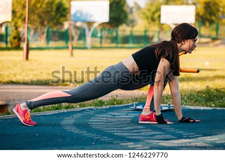 The young woman gym in the park. Fitness in the nature. Morning exercise with beautiful, sport woman. Girl doing a workout in the Park stretches the leg muscles