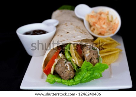 Delicious meatball wrap with salad inside with isolated black background