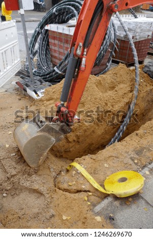 Excavation work by an excavator for laying cables on a construction site.
