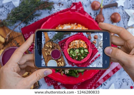 Phone food photography for social networks posts, restaurants, cafes with hands holding smartphone camera. Vegan, vegetarian lunch on table. Spinach cucumber sauerkraut salad on plate