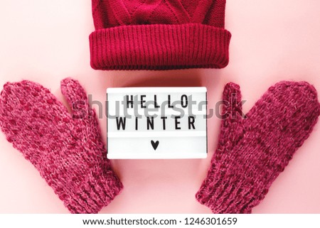 Warm, cozy winter clothing,hat, mittens lightbox on pastel pink background. Christmas concept flat lay. Stylish winter clothes. Hello winter title