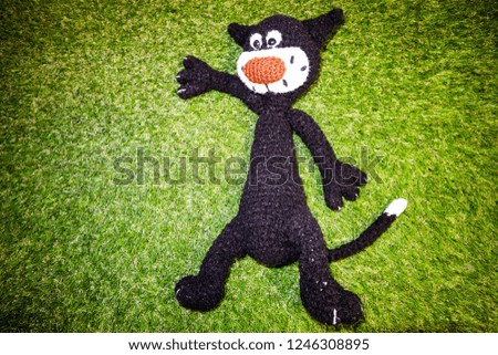 Black toy cat on green grass background