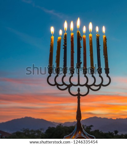 Menorah with burning candles is traditional symbol for Hebrew Holidays and celebration of Hanukkah. Background of night or dawn sky, selective focus on menorah