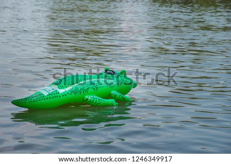 Inflatable green crocodile on the water.