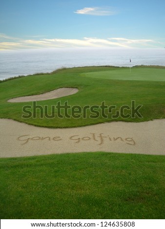           Gone Golfing handwritten in the sand on a golf course with an ocean view