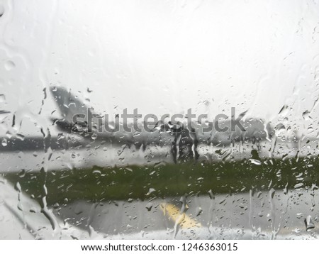 Droplet on glass window of airplane during departure when raining, with aircraft background.