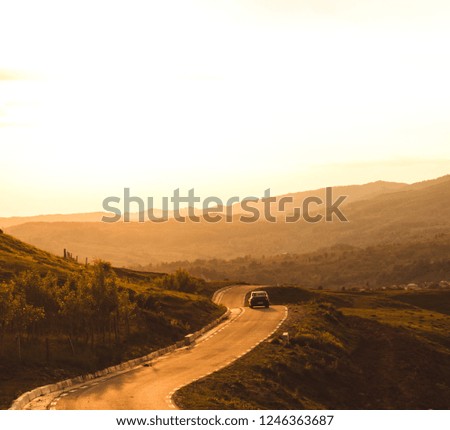 Winding road into sunset with car