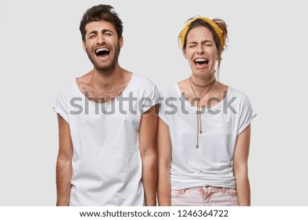 Depressed family couple cry desperately, feel negative emotions, wear white casual t shirt, frown faces in despair, model over studio wall, find out tragic news. Stressful woman man with unhappy look Royalty-Free Stock Photo #1246364722