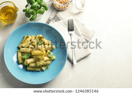 Flat lay composition with plate of delicious basil pesto pasta and space for text on gray table