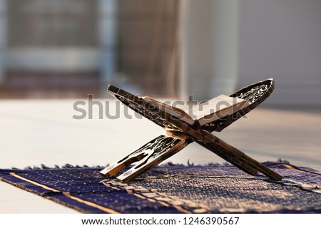 Rehal with open Quran on Muslim prayer mat indoors Royalty-Free Stock Photo #1246390567