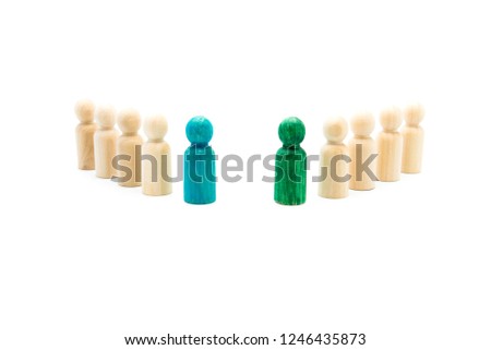 Wooden figures in line as business team, with blue and green figures standing out from the crowd, isolated on white background. Conceptual image of leadership and being different