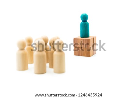 Wooden figures as a group listening to one blue figure helding speech, isolated on white background
