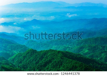 The topography of the complex green mountains and foggy sky.