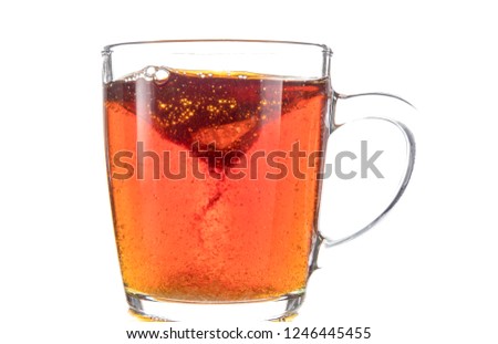 Dissolving a piece of sugar in tea in a transparent mug on a white background, a storm in a glass	