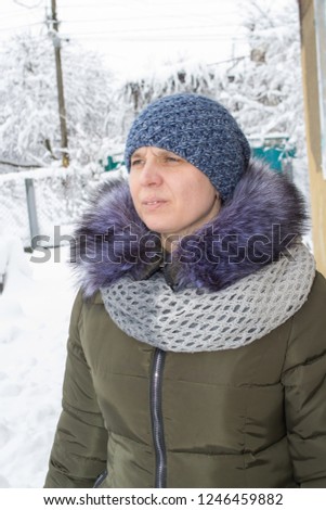 woman looks in the winter,woman in winter in snow portrait, in street of european city. Christmas, winter holidays concept. Snowfall.