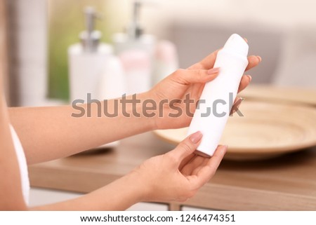 Young woman holding deodorant in bathroom, closeup