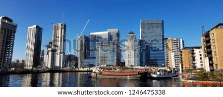 Office skyscrapers at Canary Wharf Business District. Canary Wharf is the main financial district in London. Morning blue sky and some boats present.