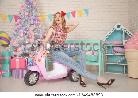 Slim Pin Up Style Girl Posing In Creative Childish Room In Christmas Eve with Big New Year Tree and Huge Cake, Giant Macaroons and Candy With Stripes
