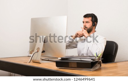 Telemarketer man in a office showing a sign of silence gesture