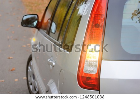 Modern grey hatchback car showing with turn signal lights beginning of moving on the road on the countryside Royalty-Free Stock Photo #1246501036