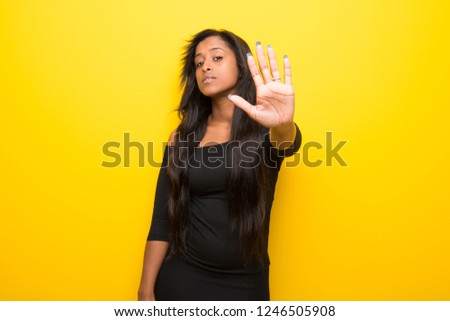 Young afro american woman on vibrant yellow background making stop gesture denying a situation that thinks wrong