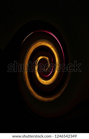 abstract graphic representation of a yellow orange coloured spiral or nebula, similar to a galaxy on a black background. The conceptual structure consists of different lights and colours