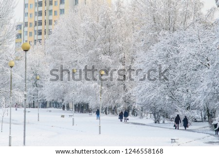 Winter cityscape in the park. People go about their business in the snowy park. Winter landscape background