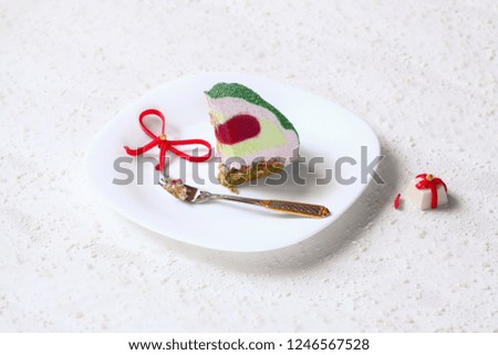 Piece of Contemporary Christmas Pistachio Red Berries Mousse Cake, on white background.