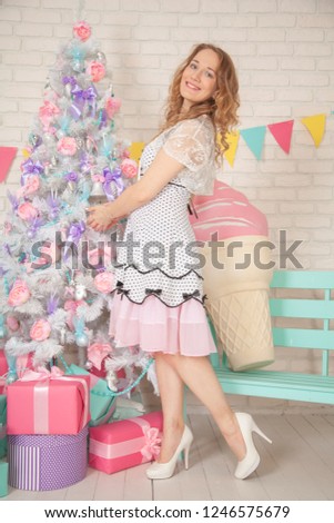 christmas girl with boxes of presents on colorful holiday background with white new year tree with flowers