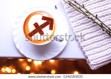 A cup of cappuccino coffee with a zodiac sign pattern Cinnamon Archer on milk foam