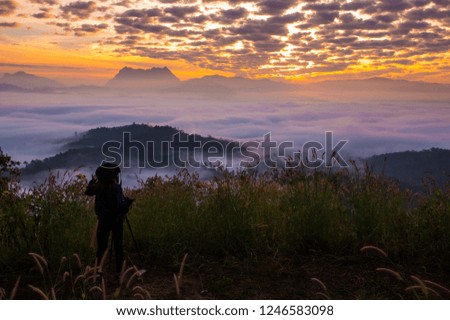 Photographer women take a photo of sunlight sky from mountain top.