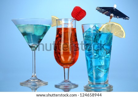 Alcoholic cocktails with ice on blue background