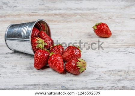 A bucket of fresh ripe strawberries, close-up on a light wooden background, copy space.