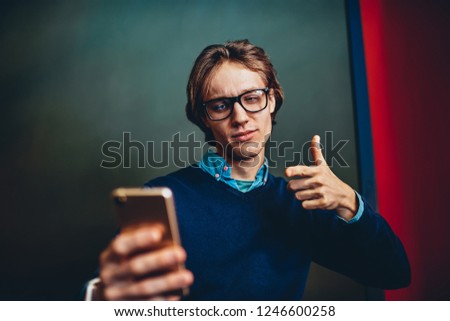 Young caucasian male showing ok sign during online conversation with friend using camera and application on smartphone, handsome hipster guy gesture thumb up making video call via mobile phone