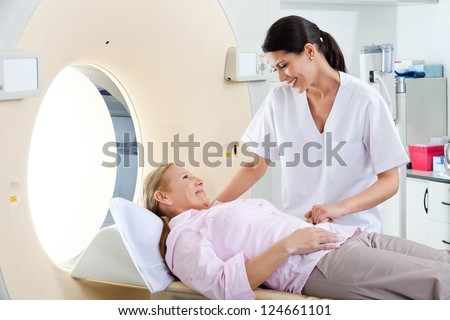 Radiologic technician smiling at mature female patient lying on a CT Scan bed Royalty-Free Stock Photo #124661101