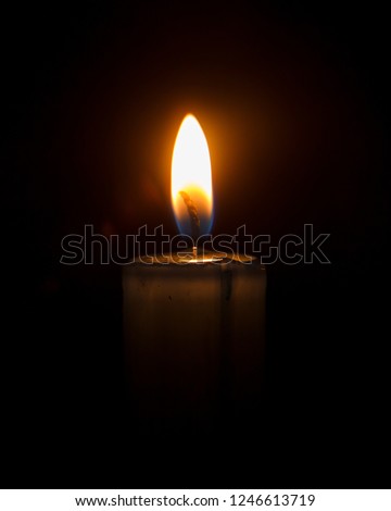 Candle on the black background. Single candle in the dark. Candle light in the darkness.