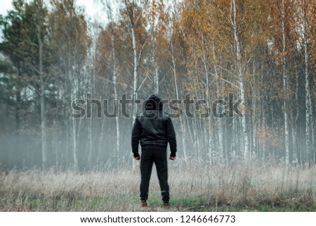 Creative background, Man, man in a black coat in foggy weather, against the background of the forest. The concept of mysticism, autumn, cold, ghost, shepherd.