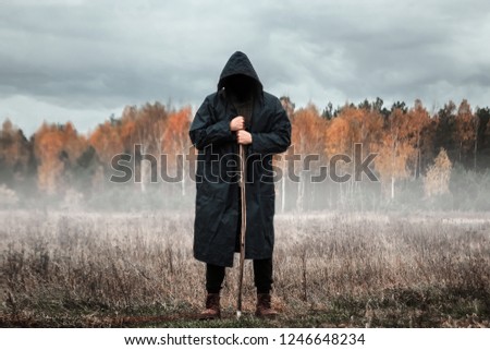Creative background, Man in a black coat in foggy weather, against the background of the forest. The concept of mysticism, autumn, cold, ghost, shepherd.