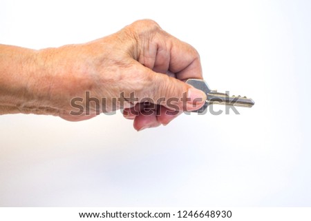 Senior woman's left hand holding key isolated on white background