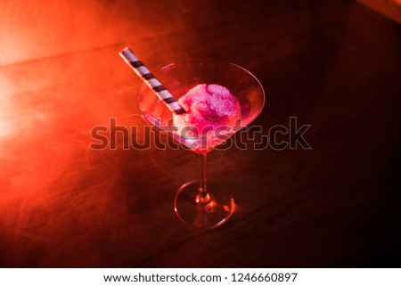 Martini glass filled with colorful fruit ice cream on dark background with toned light and fog. Selective focus