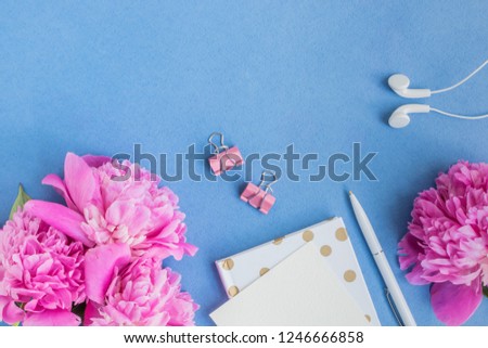 Flat lay desk with pink peonies on a blue background