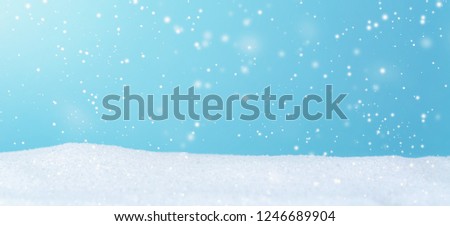 Snowfall over blue sky in a snow covered landscape