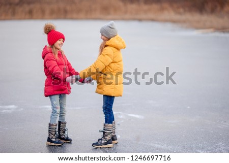 Adorable little girls having fun together on frozen lake