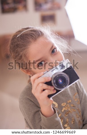 Girl with a retro camera makes a photo, studio shot.