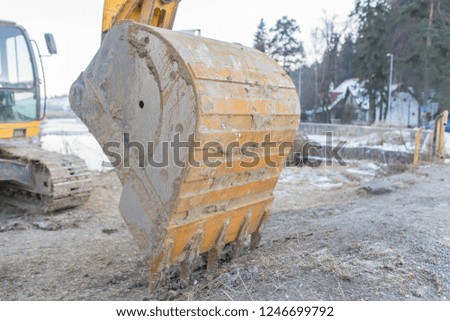 Excavator work tool close up shot near a frozen river at wintertime.