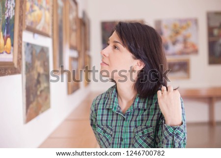 A young beautiful woman looking at painting in an art gallery.
