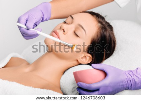 young woman getting a face mask, facial cleansing facial treatment at spa salon Royalty-Free Stock Photo #1246708603