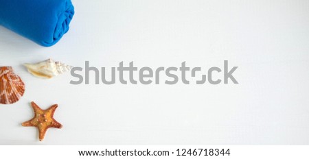 Concept on the marine theme. Seashells, towel on a white wooden background. Travel background