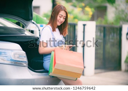 Girl sitting on her car. With many shopping bags. Online ordering by phone